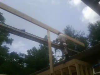 Carpenter setting a ridge beam over a new addition frame — Ice Dam Removal by Roofing Brothers in Glade Park