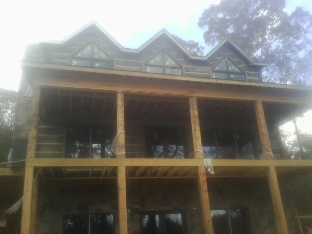 Dormers and porch framing on a large log home under construction — Roof Coating work by our crew in Glade Park