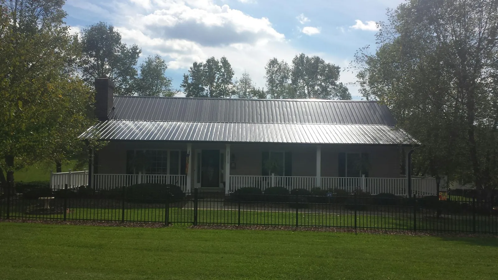 Gray metal roof on a brick ranch with a full width front porch — Gutter Guard Installation work by our crew in Glade Park