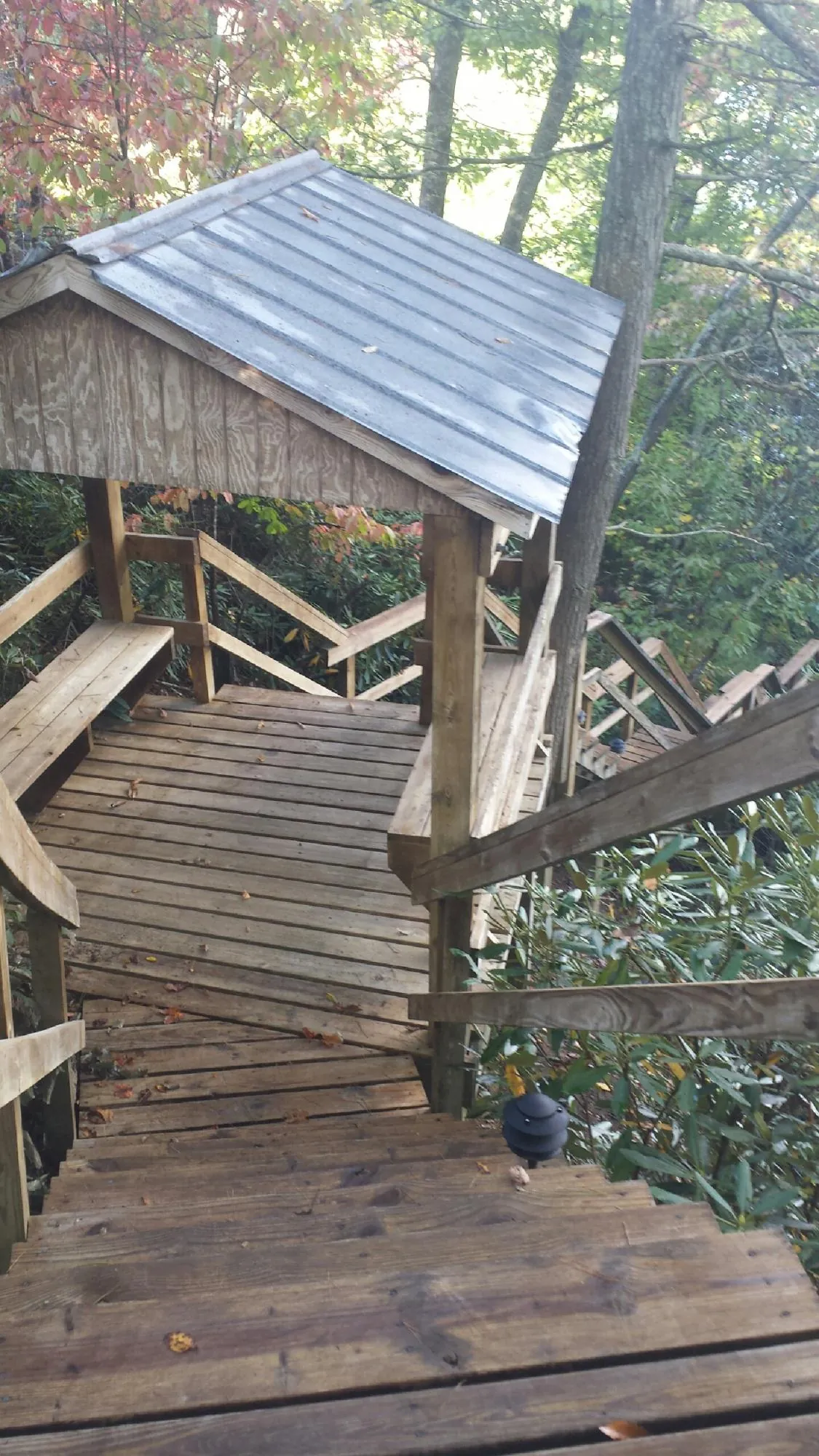 Metal roofed shelter over wooden steps on a wooded walkway — Skylight Repair & Installation work by our crew in Glade Park